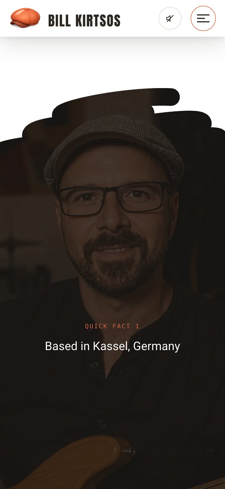 Quick facts on a phone: a black brush-stroke edge across the top opening onto a dark photograph of Bill Kirtsos in glasses and a flat cap, with the small terracotta label "Quick fact 1" and "Based in Kassel, Germany" in white, centred over it.