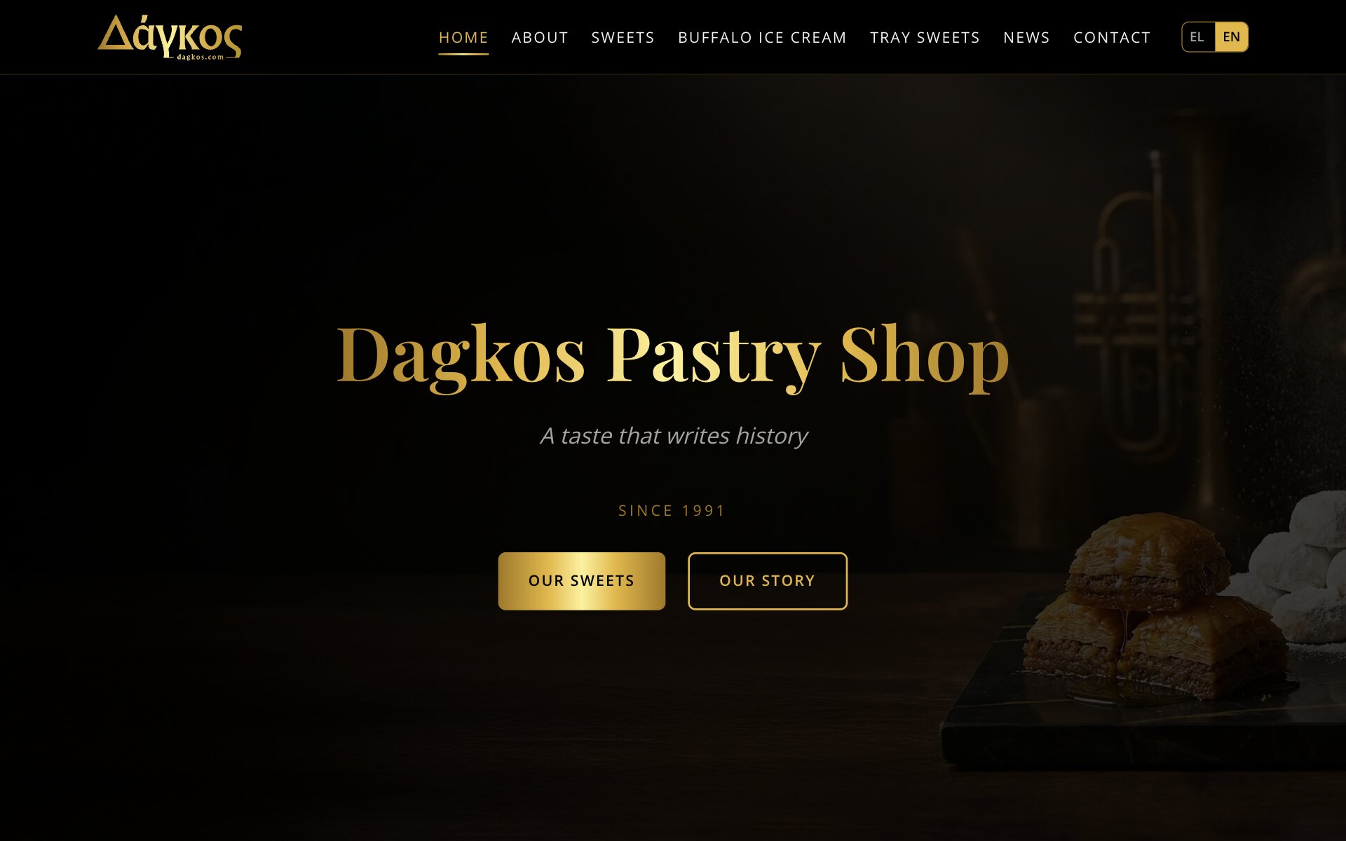 The Dagkos home page: the gold Δάγκος logo, a menu of Home, About, Sweets, Buffalo Ice Cream, Tray Sweets, News and Contact and an EL | EN switch, above a dark kitchen scene with squares of baklava on a black marble board and cookies dusted with icing sugar at the right edge; in the middle the gold heading "Dagkos Pastry Shop", the line "A taste that writes history", "Since 1991" and two buttons, a gold "Our Sweets" and an outlined "Our Story".
