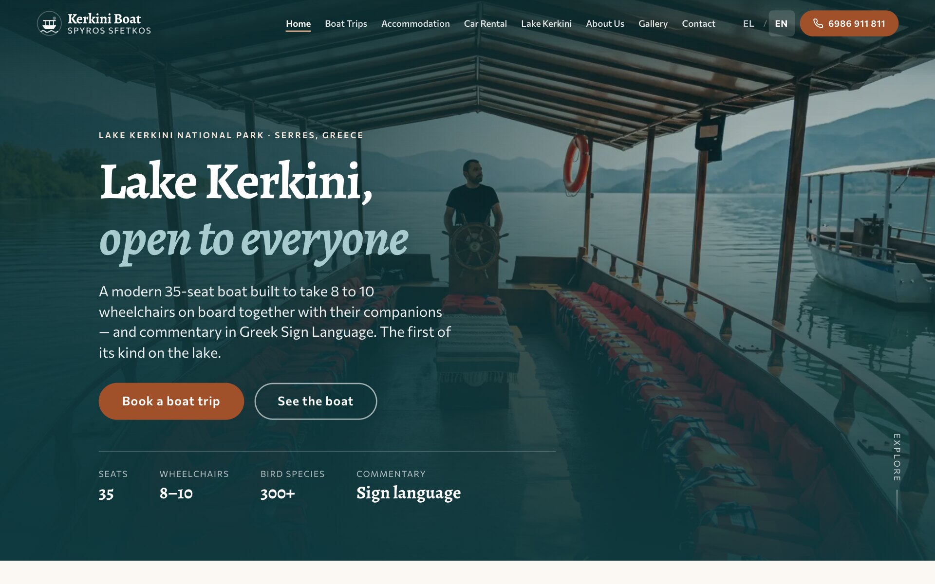 Kerkini Boat 首页:在注明塞雷斯克尔基尼湖国家公园的一行小字下方,是标题“Lake Kerkini, open to everyone”,第二行为浅色斜体;背景是一张调暗的照片:船上有顶棚的甲板,船长在掌舵,远处是湖面和群山;下方是一段简短介绍、一个铁锈色的“Book a boat trip”按钮、一个描边的“See the boat”按钮,以及四项数据:35 个座位、8–10 个轮椅位、300 多种鸟类和手语讲解。