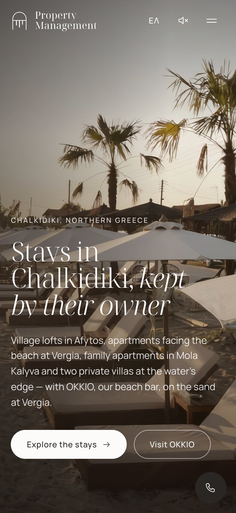 Η αρχική σελίδα σε κινητό: ο τίτλος «Stays in Chalkidiki, kept by their owner» και μια σύντομη εισαγωγή πάνω σε φωτογραφία με ξαπλώστρες και φοίνικες στην παραλία στο ηλιοβασίλεμα, με τα κουμπιά «Explore the stays» και «Visit OKKIO», έναν σύνδεσμο γλώσσας, ένα εικονίδιο ήχου και κουμπί μενού επάνω, και ένα στρογγυλό κουμπί κλήσης κάτω δεξιά.